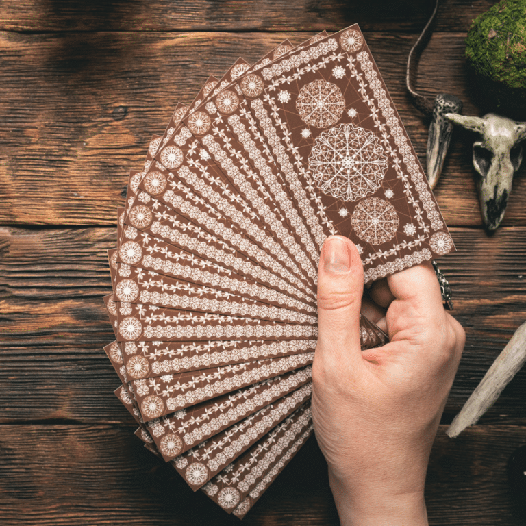 outstretched hand holding a spread of brown tarot cards