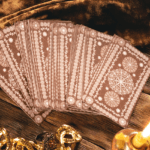A fan of brown Tarot cards on a brown table surrounded by yellow stones.