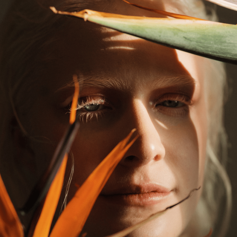 A woman peers through an exotic looking flower.