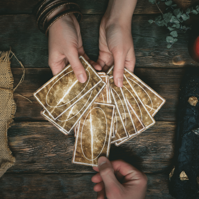 Someone's hands hold a handful of fanned out Tarot cards facing down. Someone else is choosing a card out of the fan.