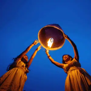 twin girls hold up a lantern ready to release it into the night sky