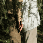 Two people stand back to back amongst some branches representing communication when mercury enters taurus, an earth sign.
