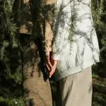 Two people stand back to back amongst some branches representing communication when mercury enters taurus, an earth sign.