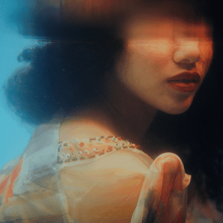 A blurred image of a woman with dark hair with half of her face underwater to represent the watery energy of Cancer.
