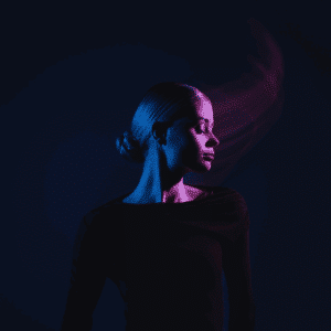 A woman wearing black with her head turned to the side is illuminated in dark blue and purple light.