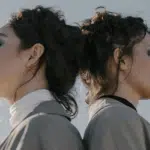 Twins stand back to back, their faces unseen, but the resemblance clear.