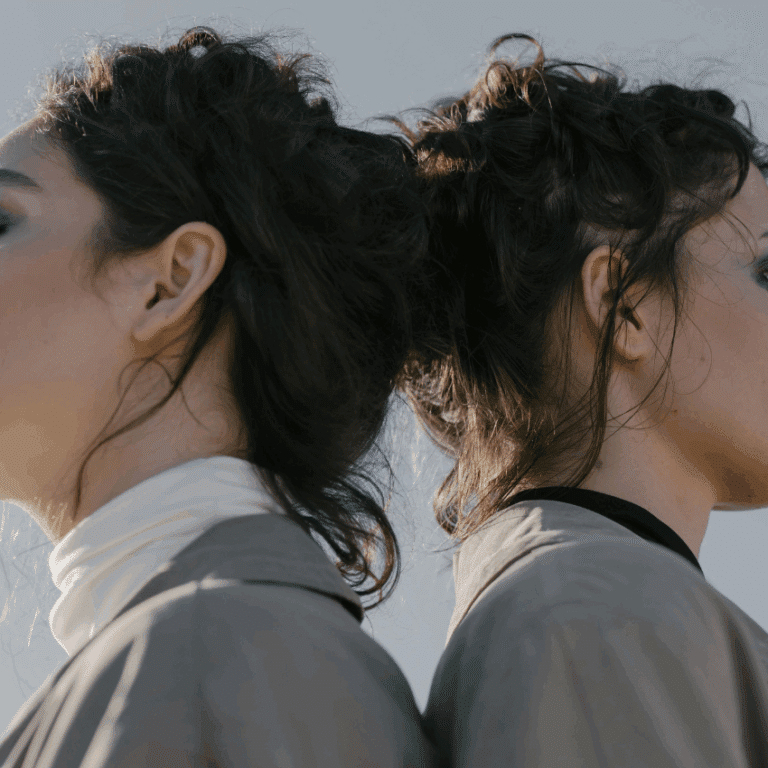 Twins stand back to back, their faces unseen, but the resemblance clear.