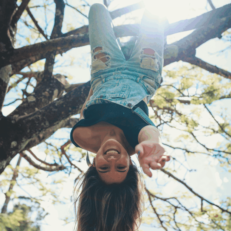 A girl hangs upside down in a tree, representing the backward nature of Saturn retrograde.