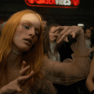 A woman with fiery red hair performs a theatrical dance in a crowd.