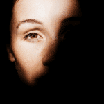 A woman's face is half shadowed to demonstrate her shadow and light sides.