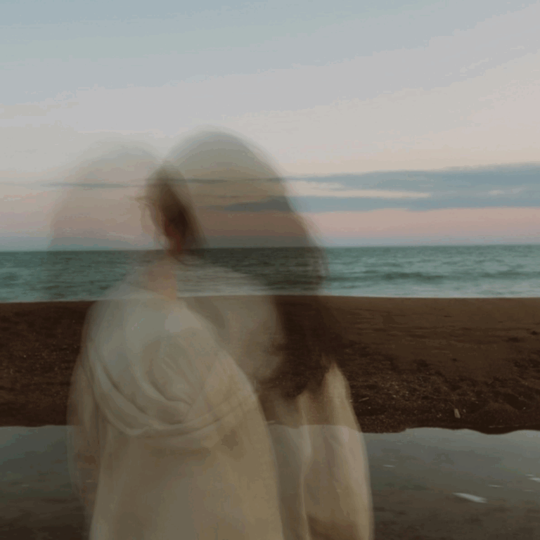 A blurred image of a woman standing next to a body of water to represent the Pisces Lunar Eclipse.