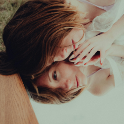 A woman lies on a mirror, showing her contemplative reflection back to her.