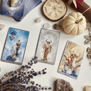 3 Tarot cards are laid out with a white pumpkin, dried lavender, various crystals to represent November 2025 Tarot Horoscopes.