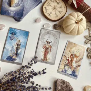 3 Tarot cards are laid out with a white pumpkin, dried lavender, various crystals to represent November 2025 Tarot Horoscopes.