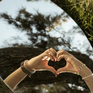 Hands are held up making a heart shape and reflected in a mirror.