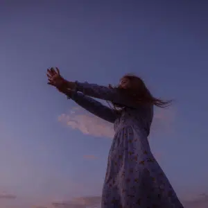 A woman stretches her arms out in front of her. The background is a light purple with a cloud behind her.