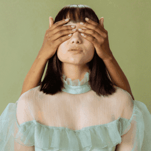 A woman wearing a green dress has someone else's hands covering her hands, representing the backwards energy of Mercury retrograde.