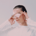 A woman wearing mirrored sunglasses looks down.