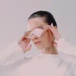 A woman wearing mirrored sunglasses looks down.