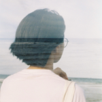 A woman faces backwards near a body of water, representing the nature of retrograde motion.