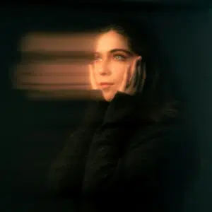 A woman's face is blurred across the image.