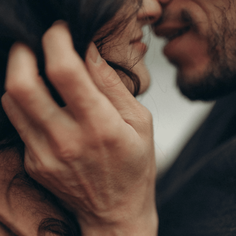 A couple are about to kiss. A bearded man holds a woman's chin with his hand to represent the most important astrological dates for love in 2026.