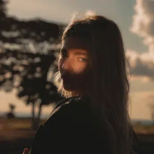 A woman looks at the camera, everything but her eyes in shadow to represent the solar eclipse.