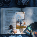 The Knight of Cups Tarot card on an open book with crystals and other assorted card in the corner.
