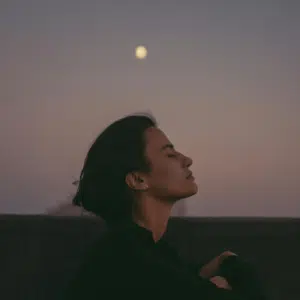 A woman with short brown hair with her eyes closed under a Full Moon in the distance to represent the Moon in Sagittarius.