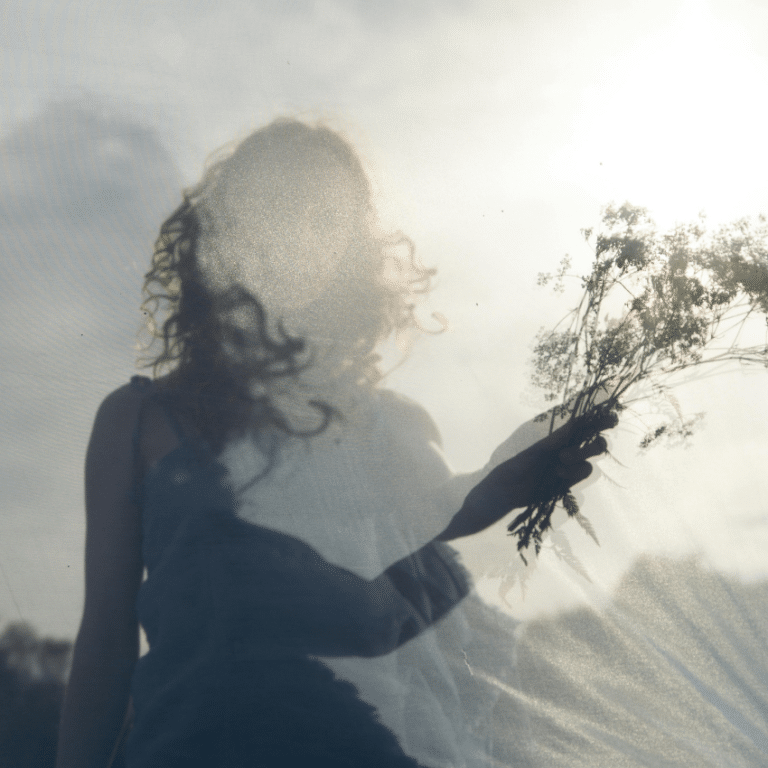 A woman holds up a small bouquet of wild florals and grasses, representing the abundant energy of April 2026.