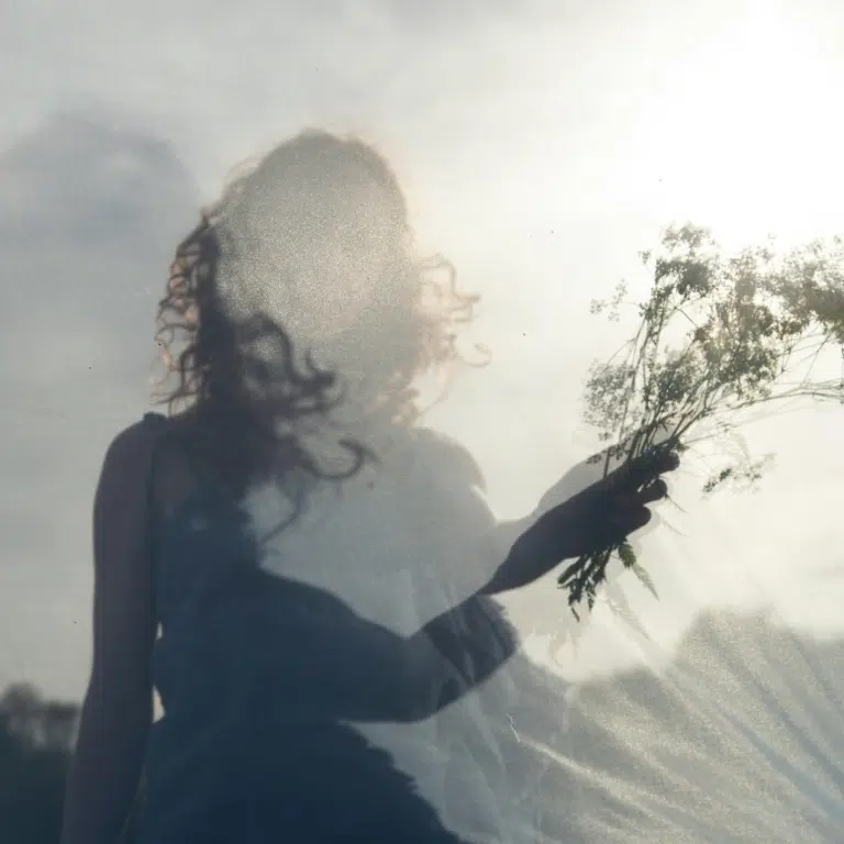 A woman holds up a small bouquet of wild florals and grasses, representing the abundant energy of April 2026.