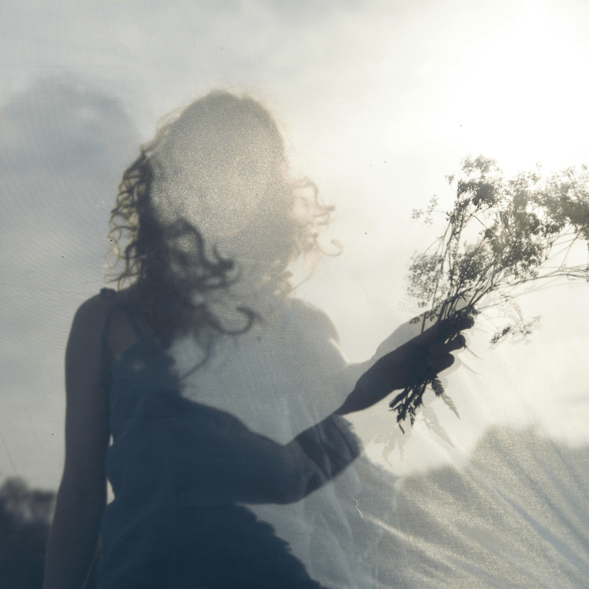 A woman holds up a small bouquet of wild florals and grasses, representing the abundant energy of April 2026.
