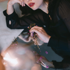 A woman's face next to a mirror, reflecting back a pool of light and her lips.