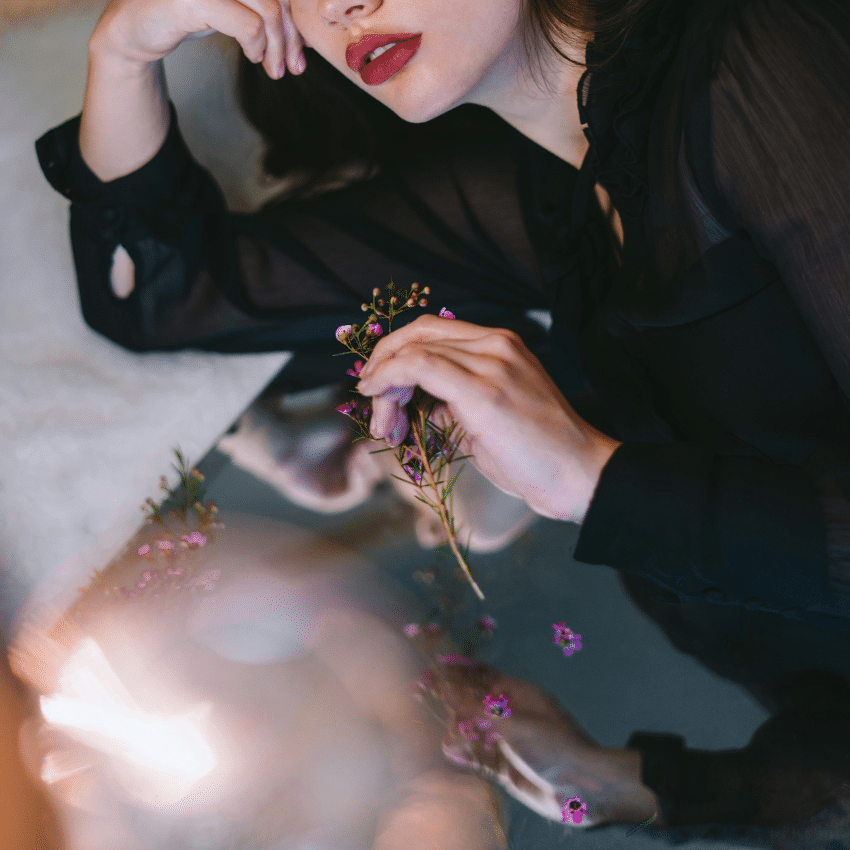A woman's face next to a mirror, reflecting back a pool of light and her lips.